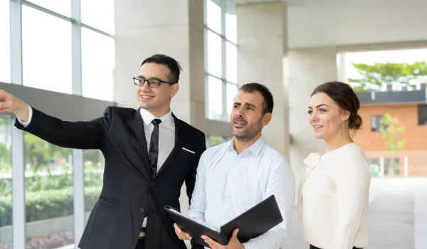 smiling-manager-showing-real-estate-object-investors-min